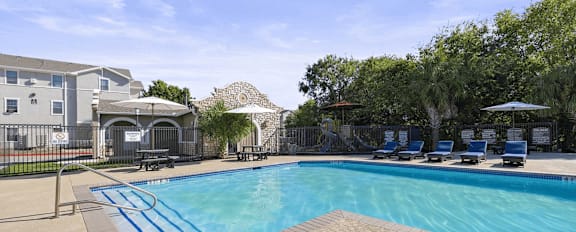 A swimming pool with a slide and a building in the background.