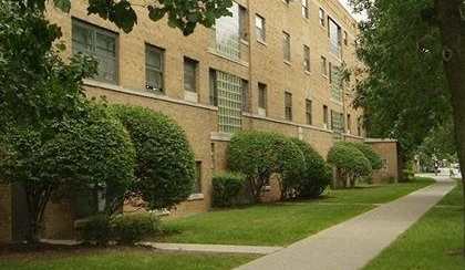 a sidewalk in front of a large brick building