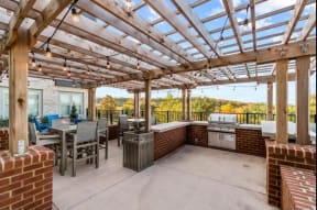 a patio with a pergola and a barbecue grill