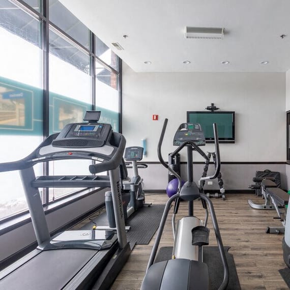 a gym with various cardio machines and a television