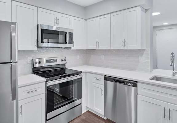 a kitchen with white cabinets and stainless steel appliances