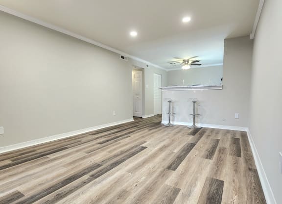 an empty living room with wood flooring and a ceiling fan