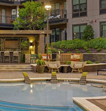 A large swimming pool in front of a building with a lounge area.