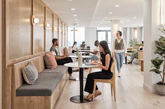 A woman in a black dress is sitting at a table in a modern office space.