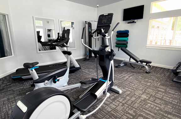 A gym with a treadmill, elliptical trainer and a stationary bike.