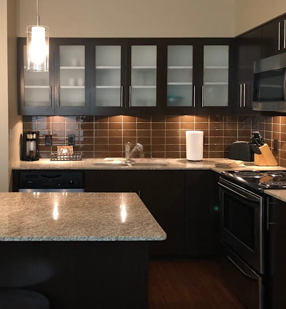 A kitchen with black cabinets and a granite counter.
