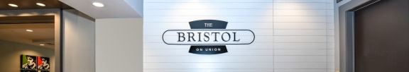 a hotel lobby with a counter and a bistro sign on the wall