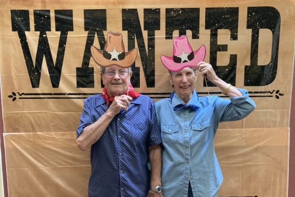 two men standing in front of a sign wearing cowboy hats