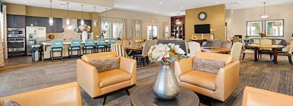 Modern apartment clubhouse with lounge chairs and dining area.