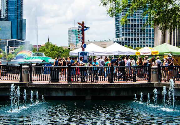 a crowd of people standing on a bridge near a fountain
