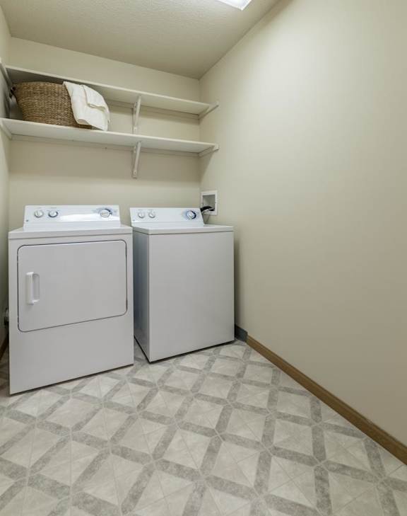 Two white washing machines in a laundry room.