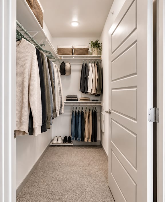 A hallway with a white door and clothes hanging on the wall.