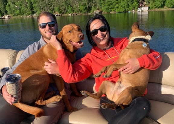 two people sitting on a boat with two dogs