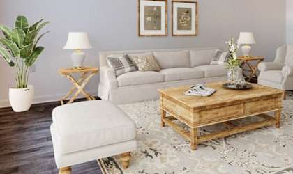 A living room with a grey couch, two chairs, a coffee table, and a potted plant.