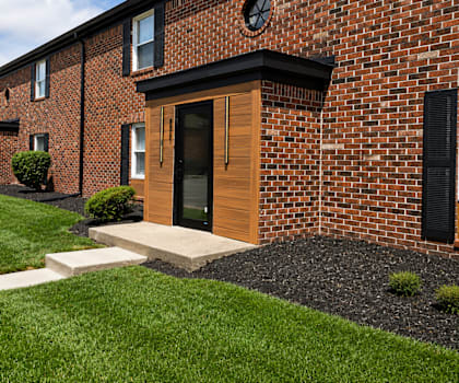 A row of red brick houses with green lawns in front.