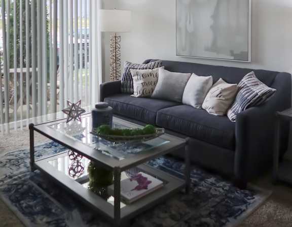 A bedroom with a large bed, a nightstand, and a window with white curtains.