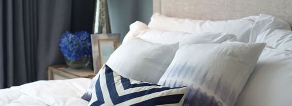 a bed with white sheets and pillows and blue and white pillows on it
