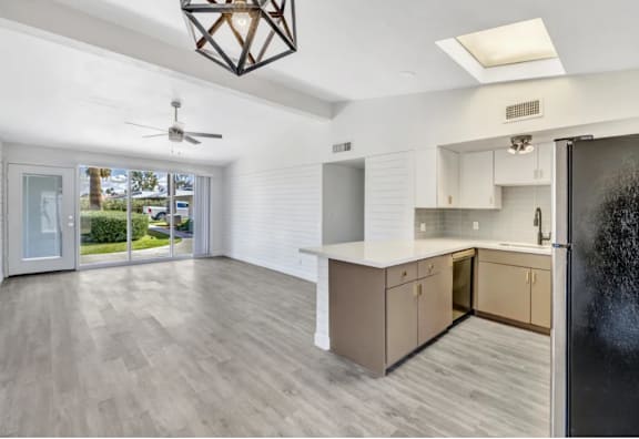 A kitchen with a black fridge and a ceiling fan.