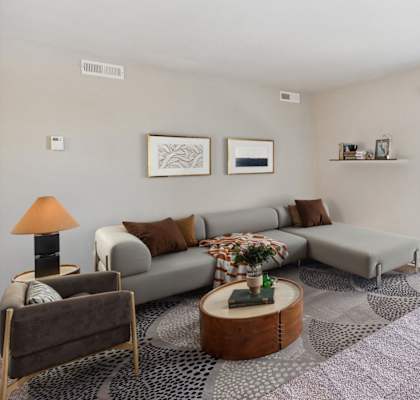 A living room with a grey couch, a coffee table, and a lamp.