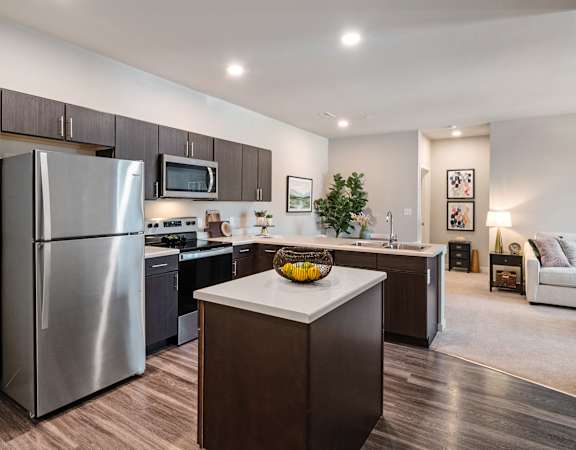 A modern kitchen with a refrigerator, microwave, and oven.