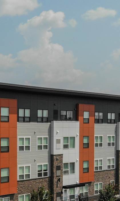 A modern apartment complex with cars parked in front.