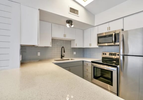 A kitchen with a granite countertop and stainless steel appliances.