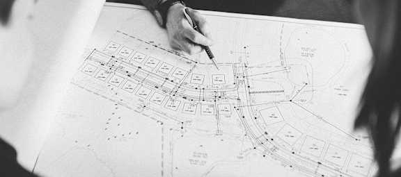Two people are working on a blueprint of a building.