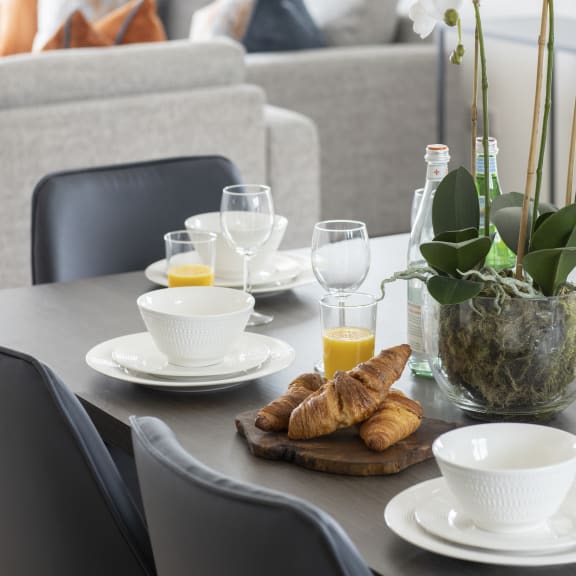 a dining table with croissants and a glass of orange juice on it