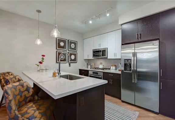A modern kitchen with a white countertop and a refrigerator.