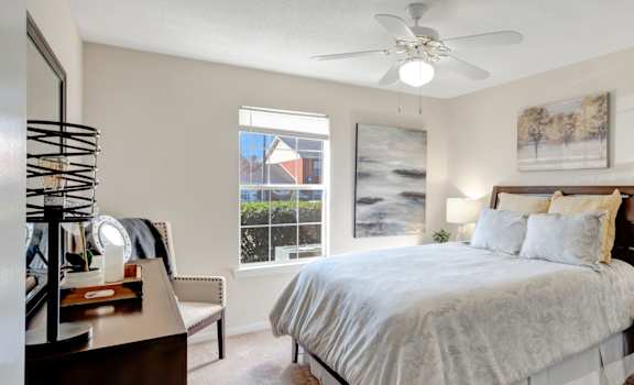 A bedroom with a large bed, a dresser, and a ceiling fan.