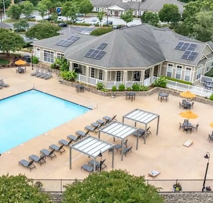 A large swimming pool surrounded by sun loungers and umbrellas in a resort-like setting.