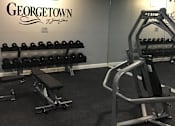 Thumbnail 15 of 26 - A gym with a row of dumbbells and a bench press.