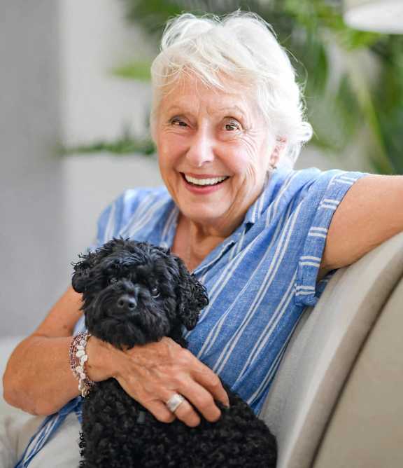 an older woman sitting on a couch smiling