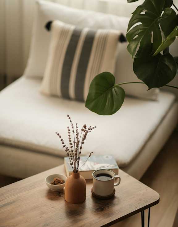 A table with a vase, a cup, and a plant on it.