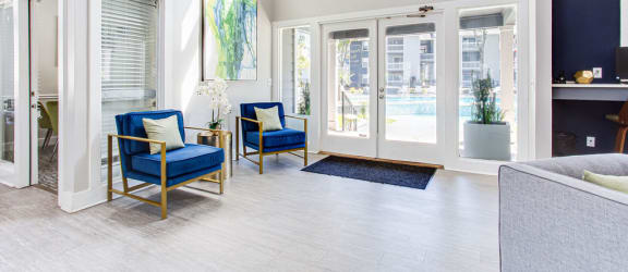 a living room with blue chairs and a door to a pool