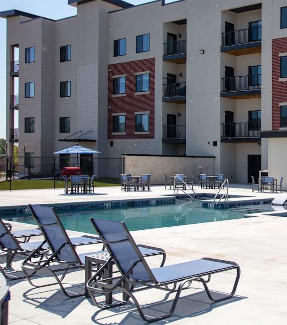 A pool area with chairs and a building in the background.