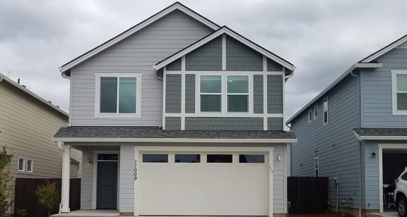 a house with a white garage door in front of a gray house