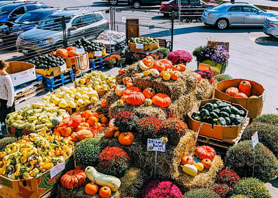 A large display of vegetables is set up outside a store named St-Leon.