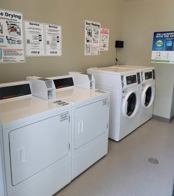 Laundry room at Lavender with two washing machines and dryers and a folding table.