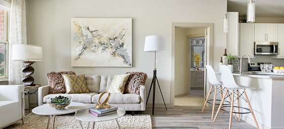A modern living room with a white sofa and a large abstract painting on the wall.
