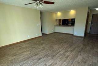 a living room with a ceiling fan and wooden flooring