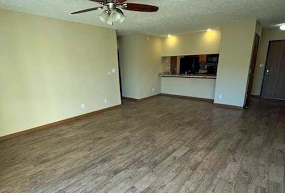 a living room with a ceiling fan and wooden flooring