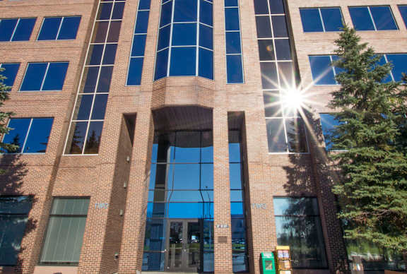 A large glass building with a sun shining through the windows.