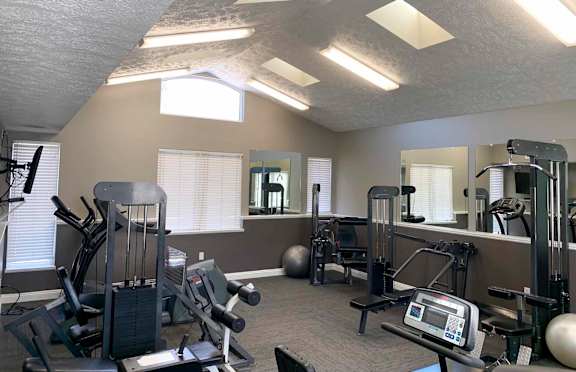 a gym with exercise machines and lights on the ceiling