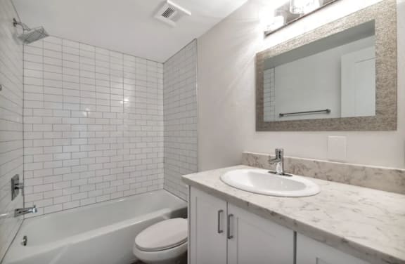 A white bathroom with a tub, toilet, and sink.