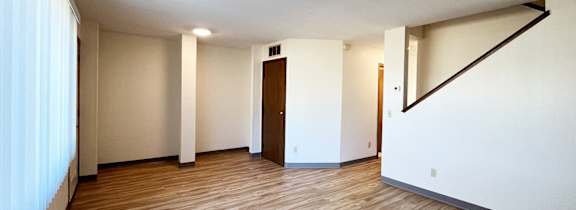 A room with wooden flooring and white walls.