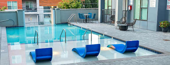 A pool surrounded by chairs and umbrellas.