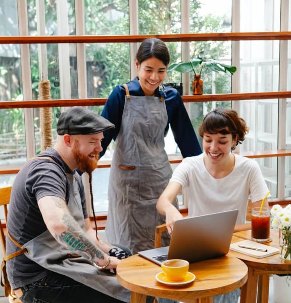 a group of people sitting around a table looking at a laptop