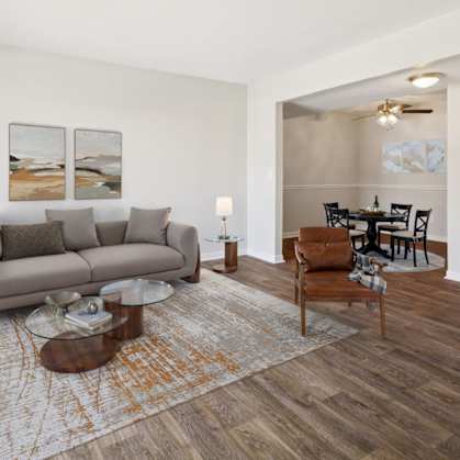 A living room with a grey couch, a coffee table, and a dining table with chairs.