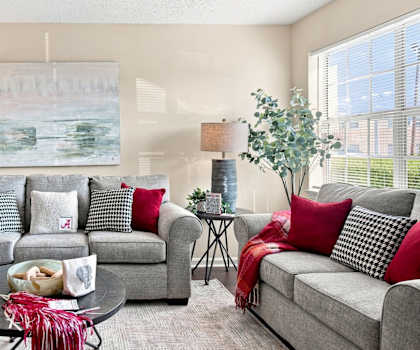 A living room with grey couches and red pillows.
